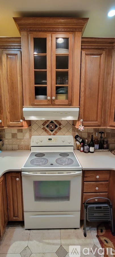 A kitchen with wooden cabinets and a white stove top oven.