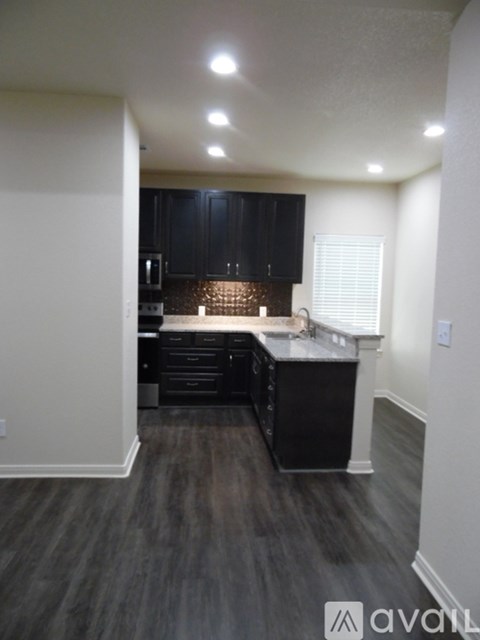 A kitchen with black cabinets and a wooden floor.