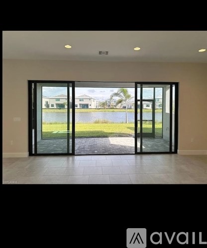 A room with a view of a green lawn through glass doors.