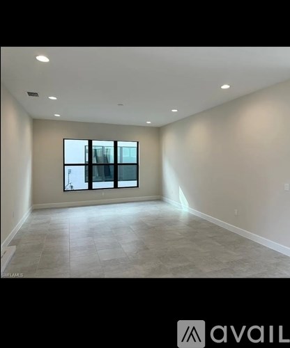 A spacious room with a large window and tiled floor.