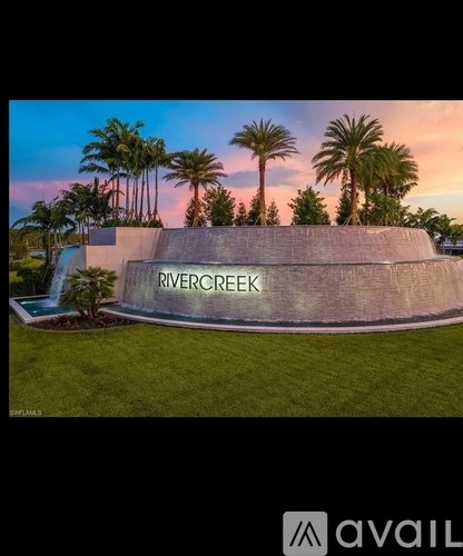 A modern building with the name Rivercreek on it surrounded by palm trees.