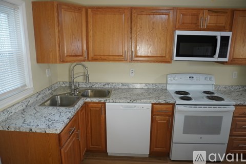 A kitchen with wooden cabinets and a white stove top oven.