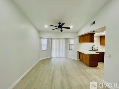 A spacious room with a ceiling fan and wooden flooring.