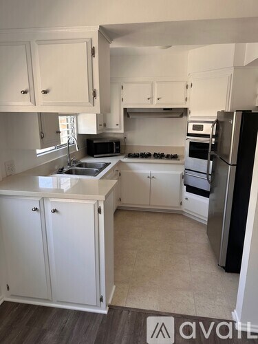 A kitchen with white cabinets and a black refrigerator.