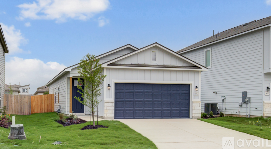 A house with a blue garage door and a tree in front.