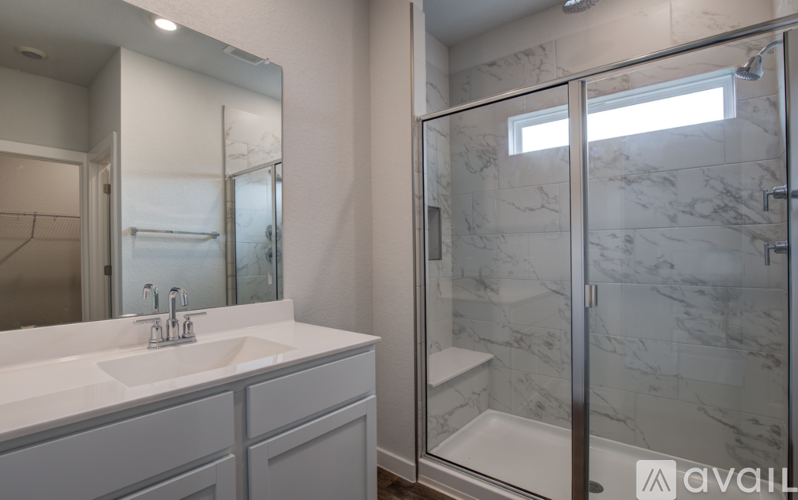 A bathroom with a marble shower and a white sink.