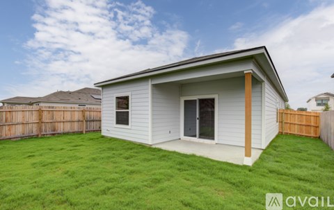 A small white house with a brown fence and a green lawn.