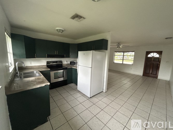 A kitchen with a white refrigerator and black cabinets.