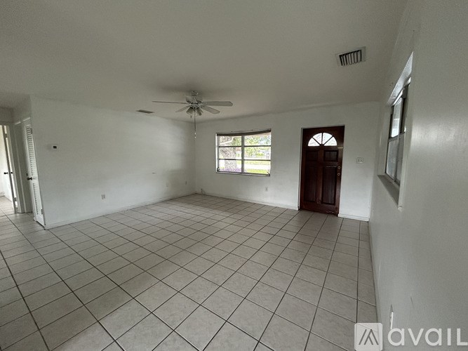 A spacious room with a ceiling fan and a door.