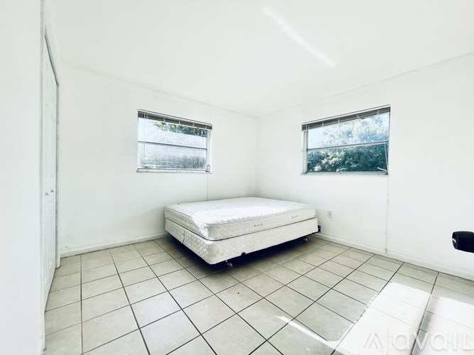 A white bedroom with a bed and two windows.