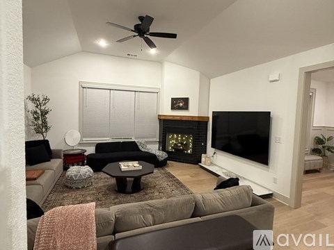 A living room with a grey couch, a coffee table, a fireplace, and a television.