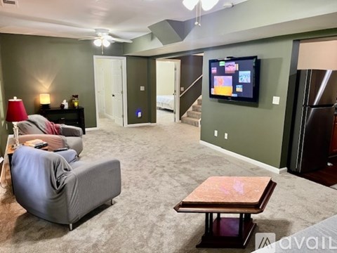 A living room with a grey couch, a wooden coffee table, and a television mounted on the wall.