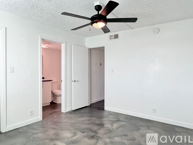 A room with a ceiling fan and a floor that looks like it has been recently mopped.