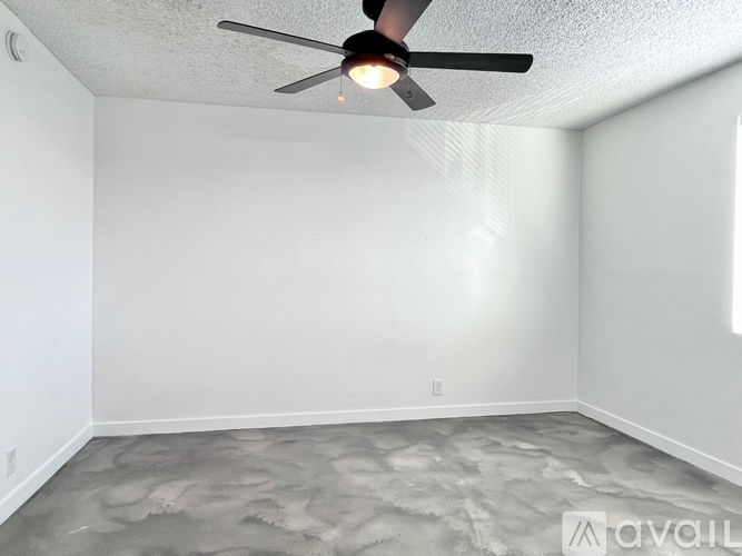 A room with a ceiling fan and a textured floor.