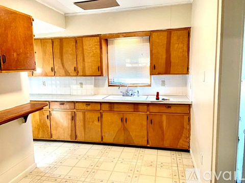 A kitchen with wooden cabinets and a tiled floor.
