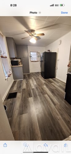 A kitchen with a black fridge and wooden flooring.