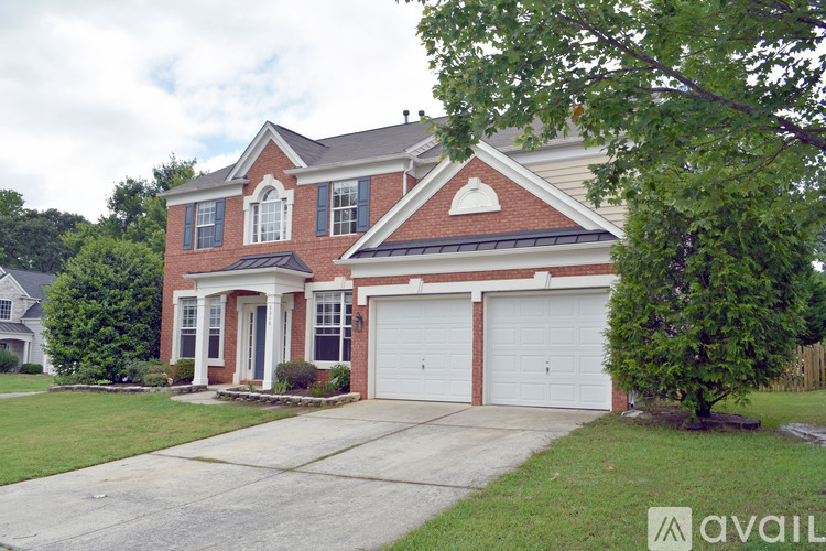 A two-story house with a brick facade and white garage doors.