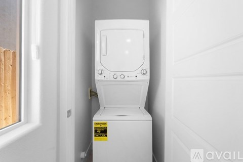 A white washing machine is in a small space next to a door.