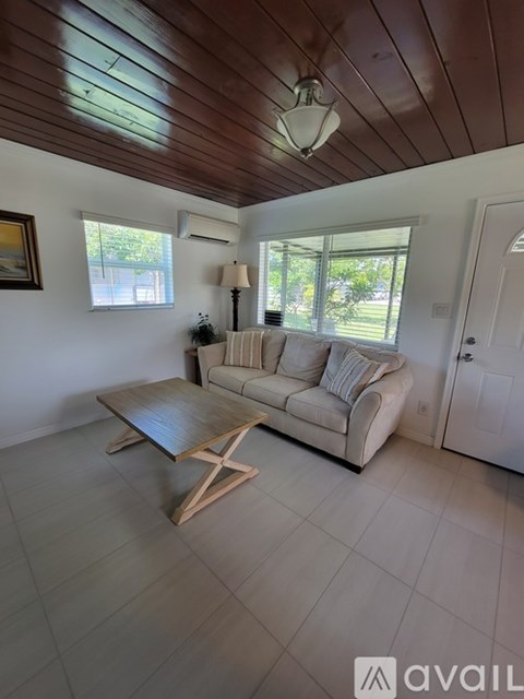 A living room with a couch, coffee table, and a painting on the wall.