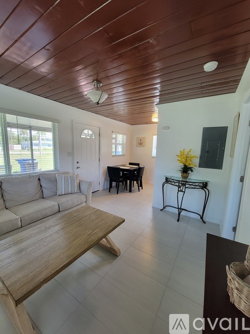 A living room with a wooden ceiling and a piano.