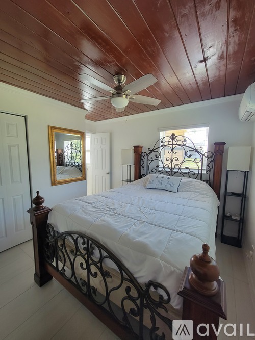 A bedroom with a bed, a ceiling fan, and a picture frame on the wall.