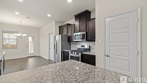 A kitchen with dark brown cabinets and a granite countertop.