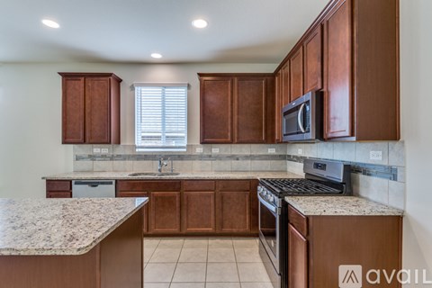 A kitchen with brown cabinets and a granite countertop.