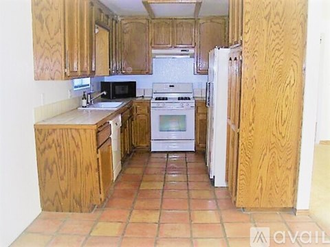 A kitchen with wooden cabinets and tile flooring.