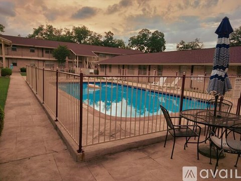 A pool surrounded by a fence and chairs.
