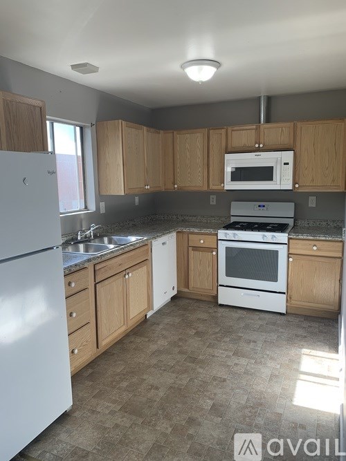 A kitchen with white appliances and wooden cabinets.