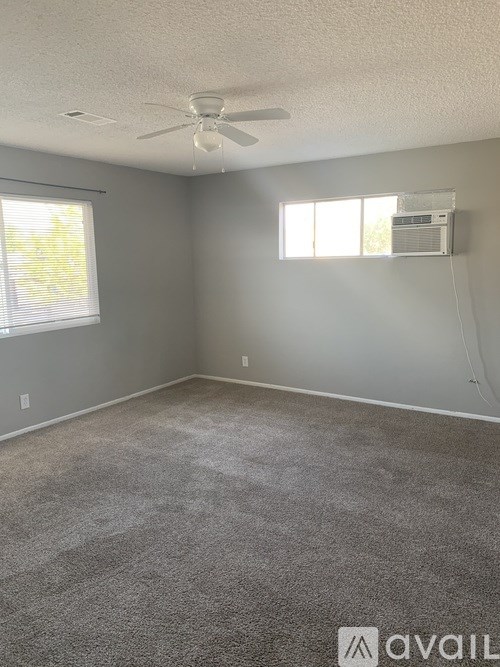 A room with a carpeted floor, a ceiling fan, and a window with blinds.
