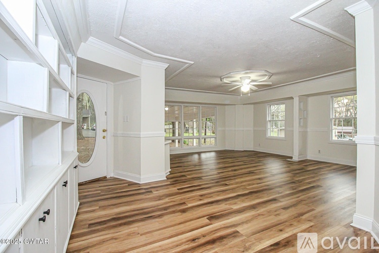 A spacious room with wooden floors and white walls.