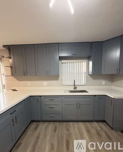 A kitchen with grey cabinets and a white countertop.