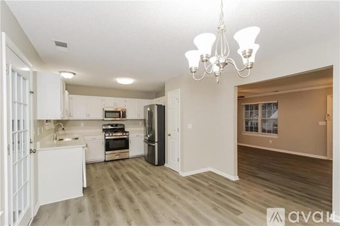 A well-lit kitchen with a chandelier and a dining area with a table and chairs.
