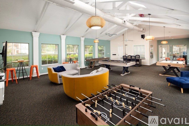 A foosball table is in the middle of a room with a couch, chairs, and a television.