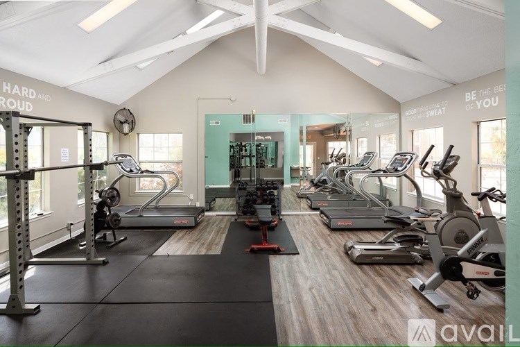 A gym with a variety of equipment including treadmills, weights, and exercise machines.