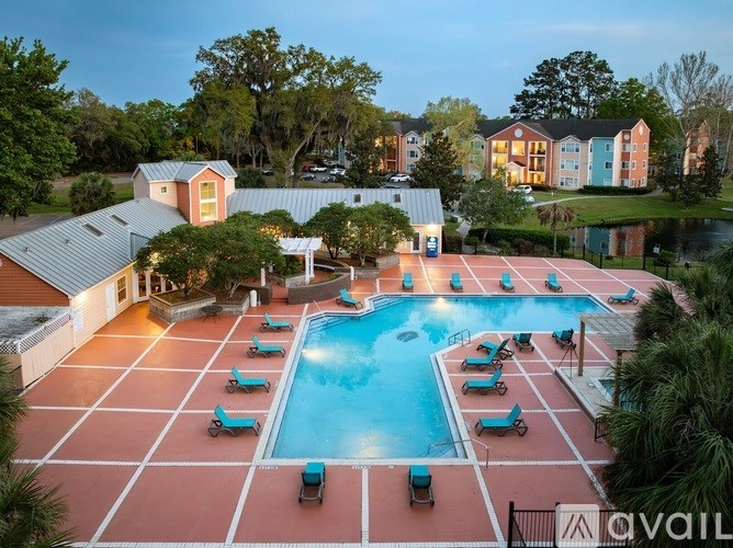 A pool surrounded by lounge chairs and umbrellas with a building in the background.
