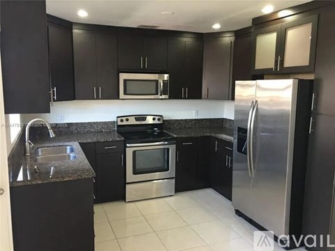 A kitchen with black cabinets and stainless steel appliances.