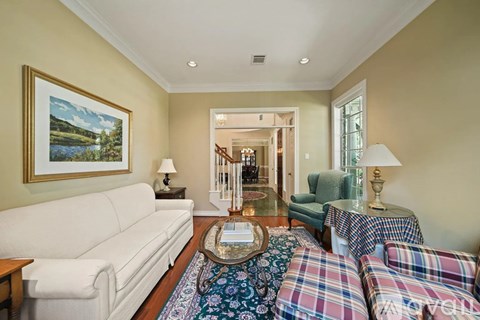 A living room with a white couch and a painting on the wall.