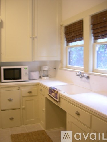 A kitchen with white cabinets and a microwave on the counter.
