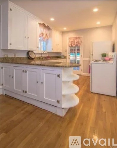 A kitchen with white cabinets and a wooden floor.