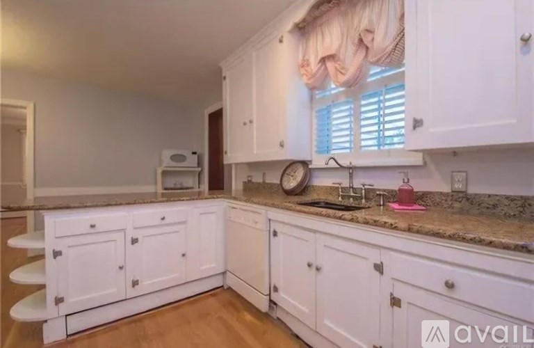 A kitchen with white cabinets and a granite countertop.