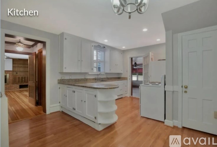 A kitchen with white cabinets and a wooden floor.
