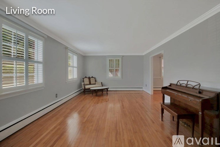 A living room with wooden floors and a window with blinds.