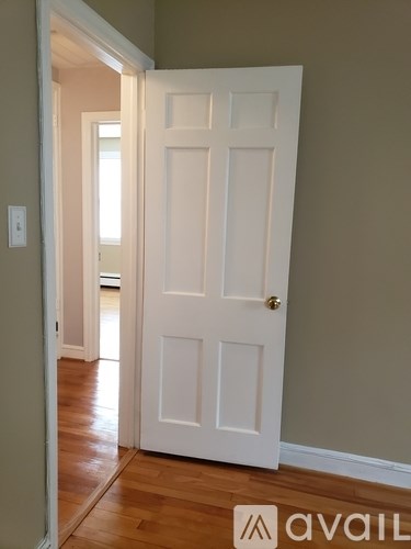 A white door with a gold handle is in a room with wooden floors.