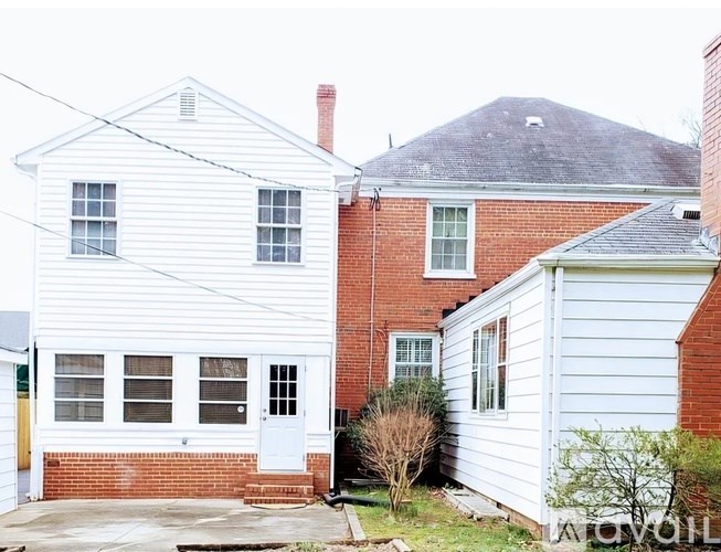 A white house with a red brick house in the background.