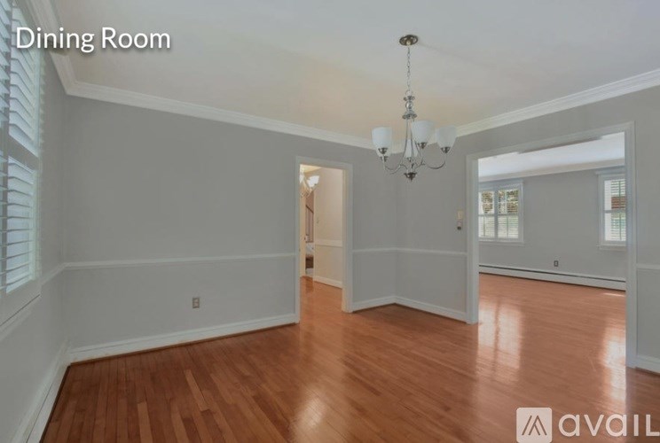 A dining room with wooden floors and a chandelier.