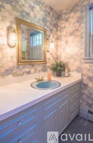 A bathroom with a stone wall and a gold framed mirror.