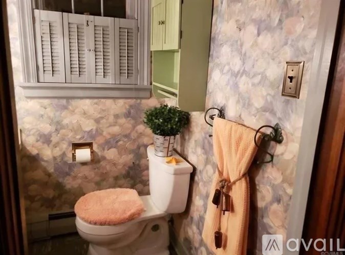 A bathroom with a toilet, a towel rack, and a plant.