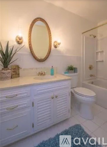 A bathroom with a white toilet, a sink with a mirror and a cabinet above it.